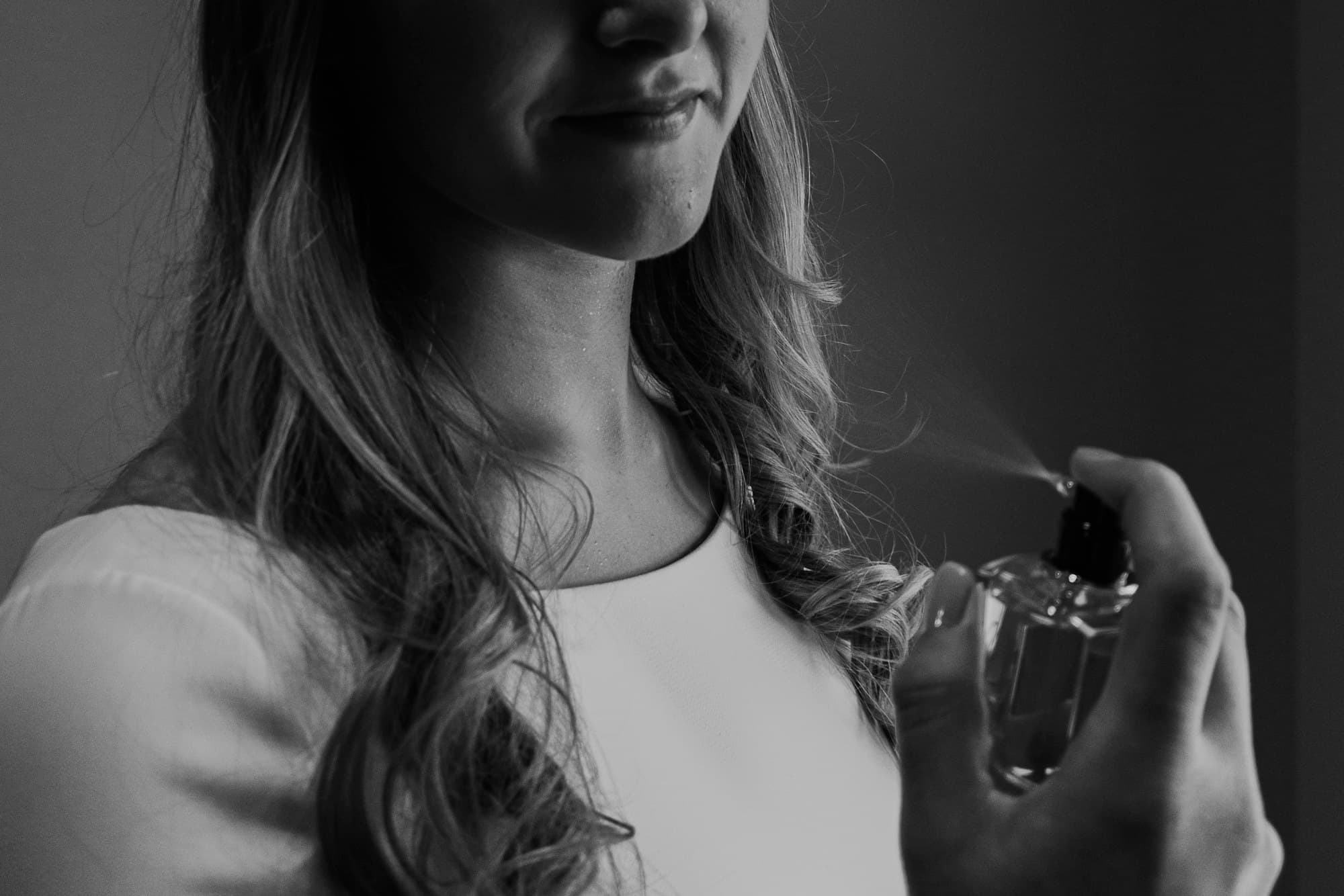 Kobieta rozpylająca perfumy z bezbarwnego flakonu, zdjęcie czarno-białe