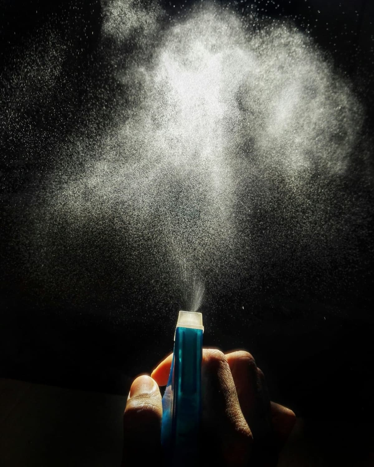 Mgiełka perfum rozpylona na ciemnym tle