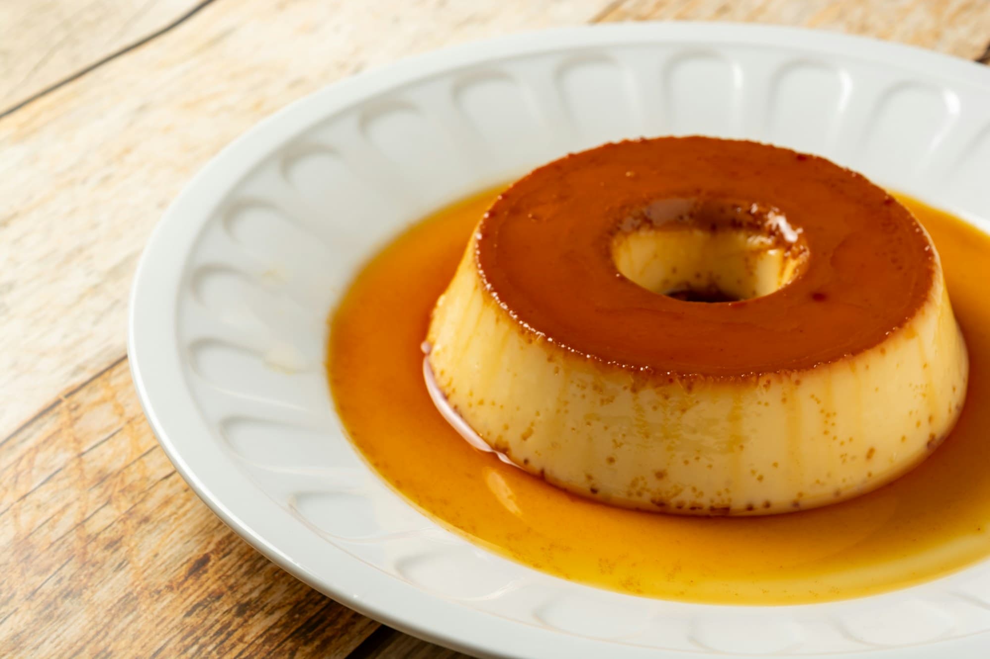 Flan karmelowy polany sosem na białym talerzu